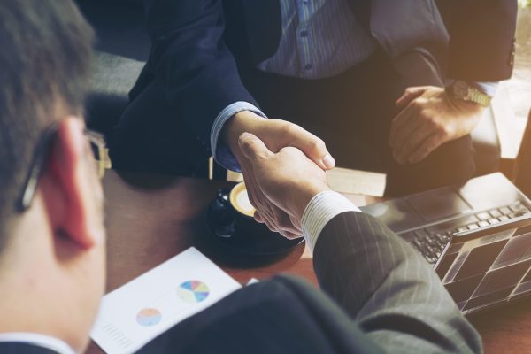 Two businessman shake hand in coffee shop