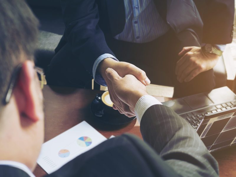Two businessman shake hand in coffee shop